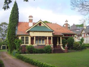 Exterior facade shot of federation house. Bright colours - red-brown, green, white. Terracotta roof. 